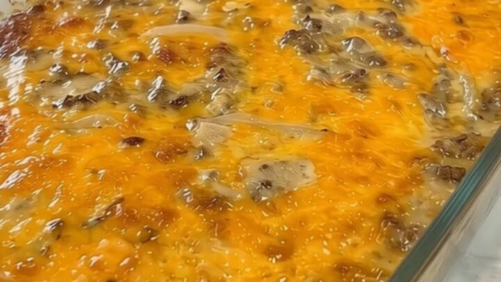 A fresh cheesy ground beef and potato casserole in a clear glass baking dish on a marble counter