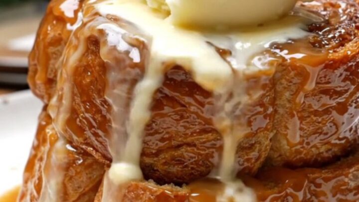 A warm, decadent Bananas Foster French toast bake in a ceramic slow cooker topped with toasted pecans.