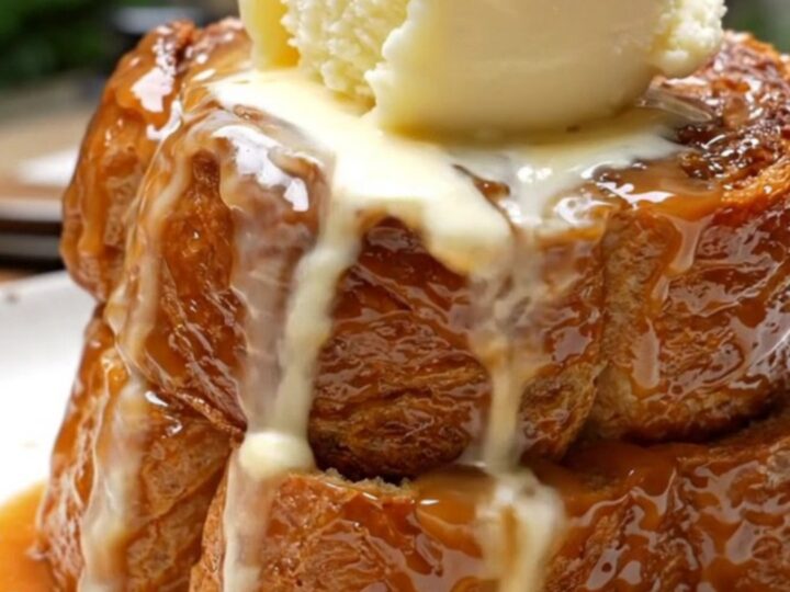 A warm, decadent Bananas Foster French toast bake in a ceramic slow cooker topped with toasted pecans.