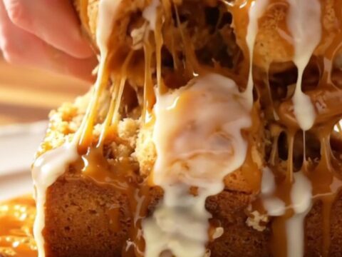 Sticky caramel pecan monkey bread served on a white platter with a piece being pulled apart to show the inside.