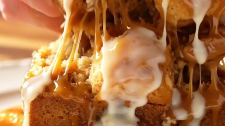 Sticky caramel pecan monkey bread served on a white platter with a piece being pulled apart to show the inside.