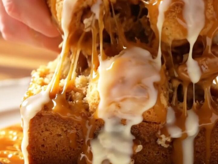 Sticky caramel pecan monkey bread served on a white platter with a piece being pulled apart to show the inside.