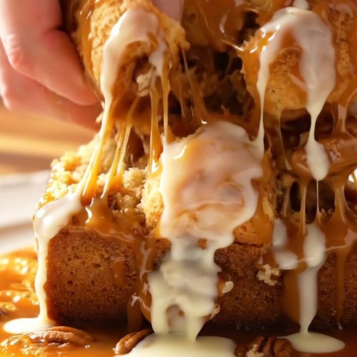 Sticky caramel pecan monkey bread served on a white platter with a piece being pulled apart to show the inside.