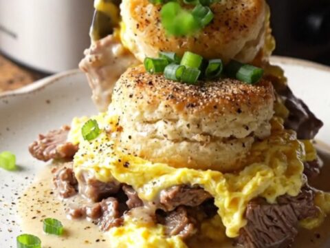 A rustic black slow cooker filled with a golden, bubbling breakfast casserole topped with green onions.