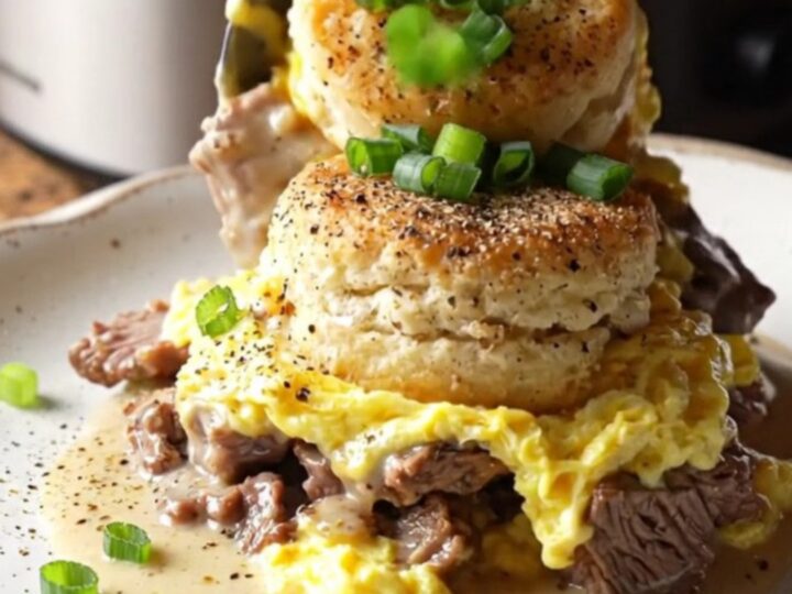 A rustic black slow cooker filled with a golden, bubbling breakfast casserole topped with green onions.