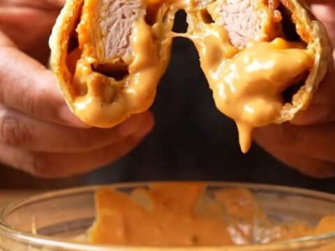 Crispy chipotle chicken wrap sliced diagonally, showing gooey cheese and creamy sauce