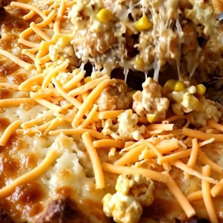 Golden chicken mashed potato bowl casserole in a white baking dish with bubbling melted cheddar edges on a granite counter