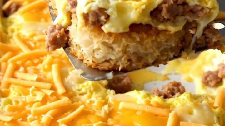 Golden hash brown patty breakfast casserole with turkey sausage and melted cheddar bubbling at the edges in a white ceramic