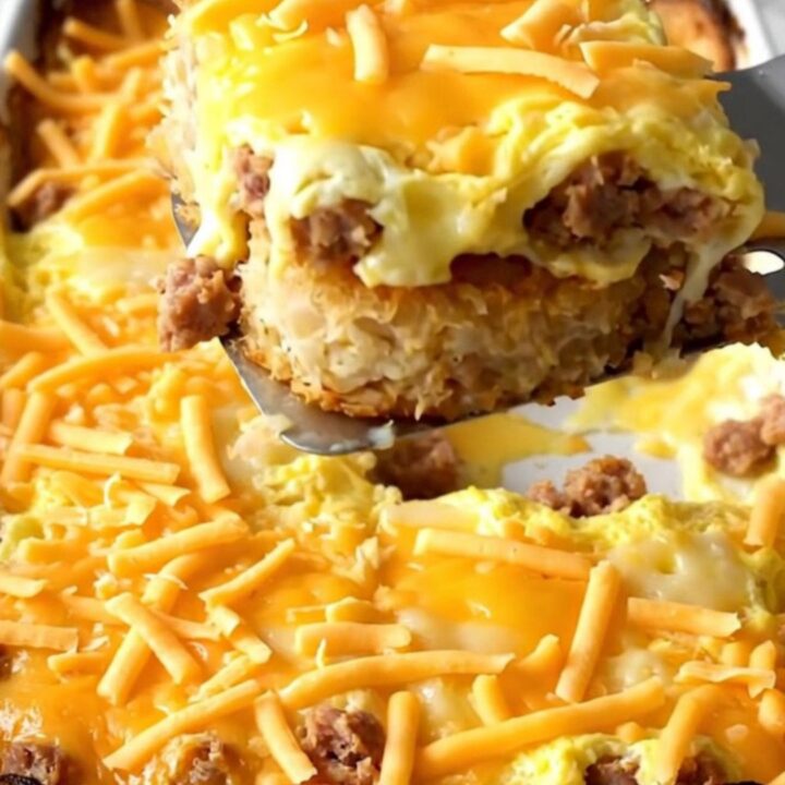 Golden hash brown patty breakfast casserole with turkey sausage and melted cheddar bubbling at the edges in a white ceramic