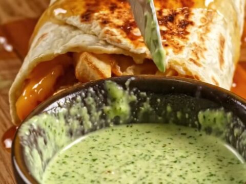 Honey butter chicken strip burrito cut in half, showing crinkle fries, melted Monterey Jack, and jalapeño ranch