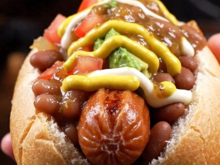 Bacon-wrapped Sonoran hot dog in a steamed bolillo loaded with pinto beans, caramelized onions, diced tomatoes