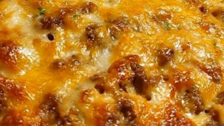 Golden baked spaghetti in a glass dish with a spatula lifting a cheesy slice and a long mozzarella pull