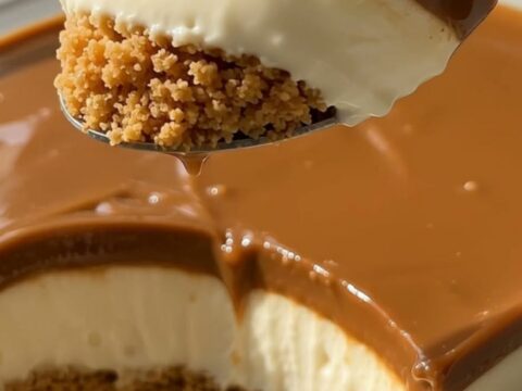Slice of creamy caramel cheesecake with graham crust and glossy caramel topping on a white dessert plate