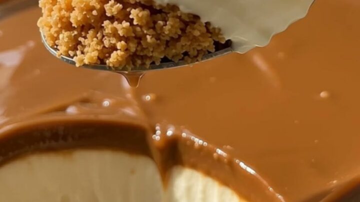 Slice of creamy caramel cheesecake with graham crust and glossy caramel topping on a white dessert plate