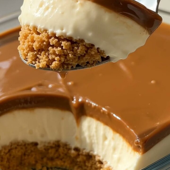 Slice of creamy caramel cheesecake with graham crust and glossy caramel topping on a white dessert plate