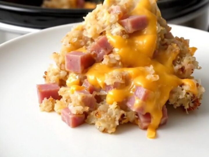 A scoop of creamy crockpot cheesy ham and hash browns steaming on a white plate