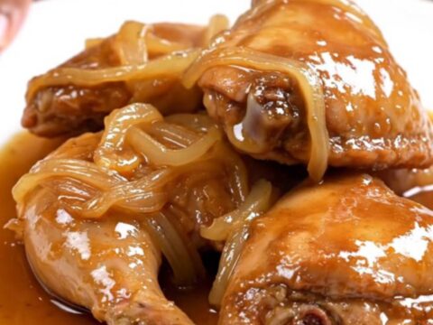 Slow cooker sweet tea chicken thighs with onions and glossy amber sauce on a white plate