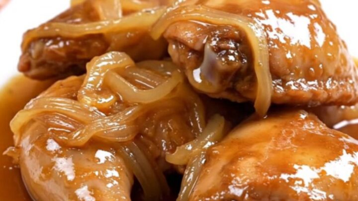 Slow cooker sweet tea chicken thighs with onions and glossy amber sauce on a white plate