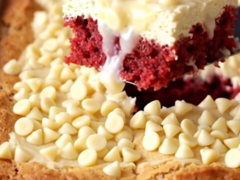 Baked red velvet gooey butter cake with pale golden top and white chocolate chips in a white ceramic dish