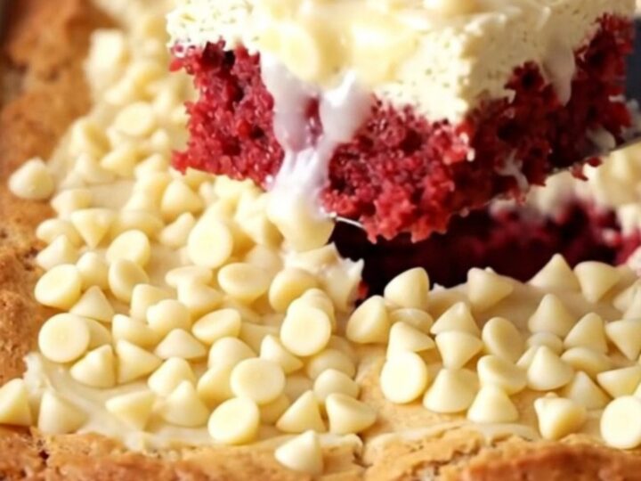 Baked red velvet gooey butter cake with pale golden top and white chocolate chips in a white ceramic dish