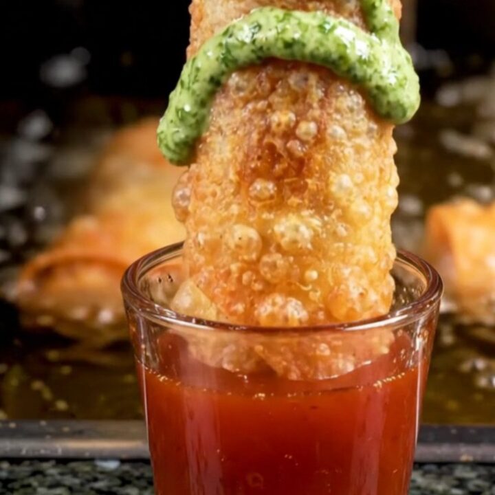 Diagonally sliced crispy birria egg roll pulled open to show braised beef and melted pepper jack