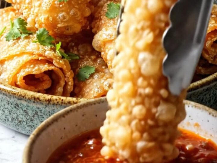 Golden crispy air-fryer cheesy taco pinwheels piled on a platter with a bowl of chunky roasted salsa