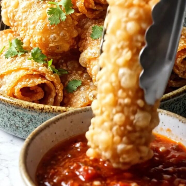 Golden crispy air-fryer cheesy taco pinwheels piled on a platter with a bowl of chunky roasted salsa
