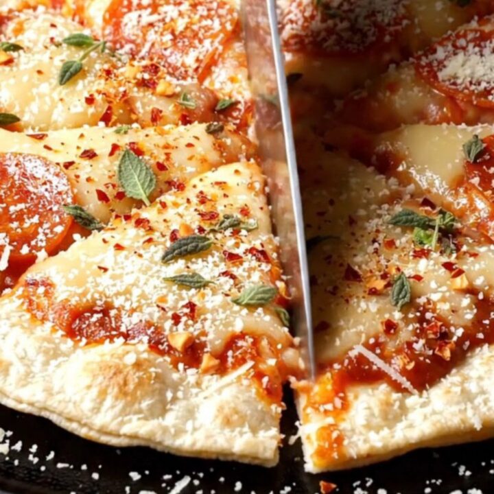 A crispy tortilla smash pizzadilla wedge lifted with a long mozzarella cheese pull, topped with charred pepperoni and chorizo