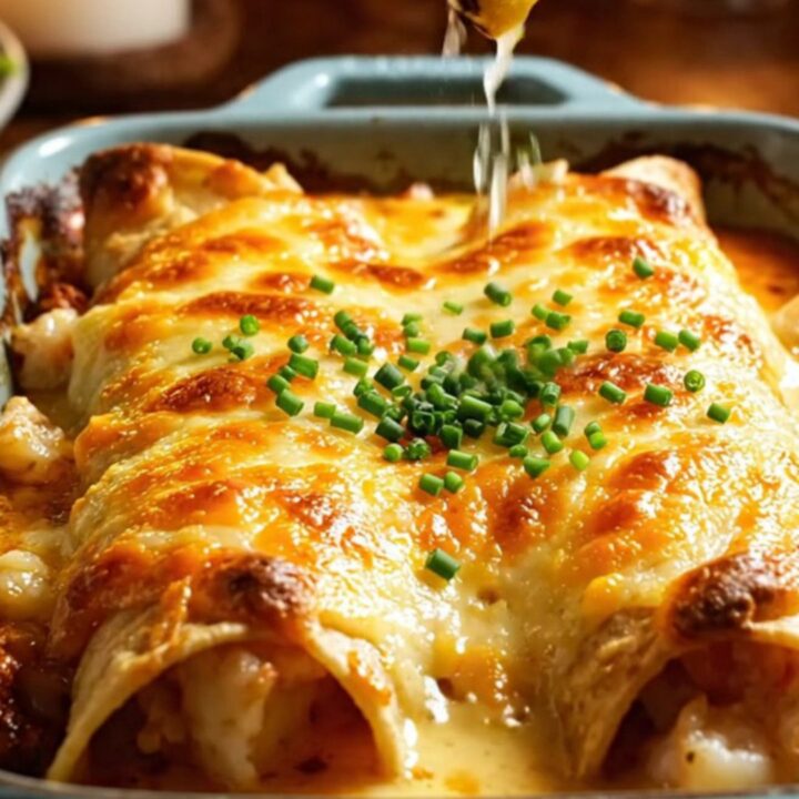 Golden blistered garlic butter crab and shrimp enchiladas in a ceramic baking dish