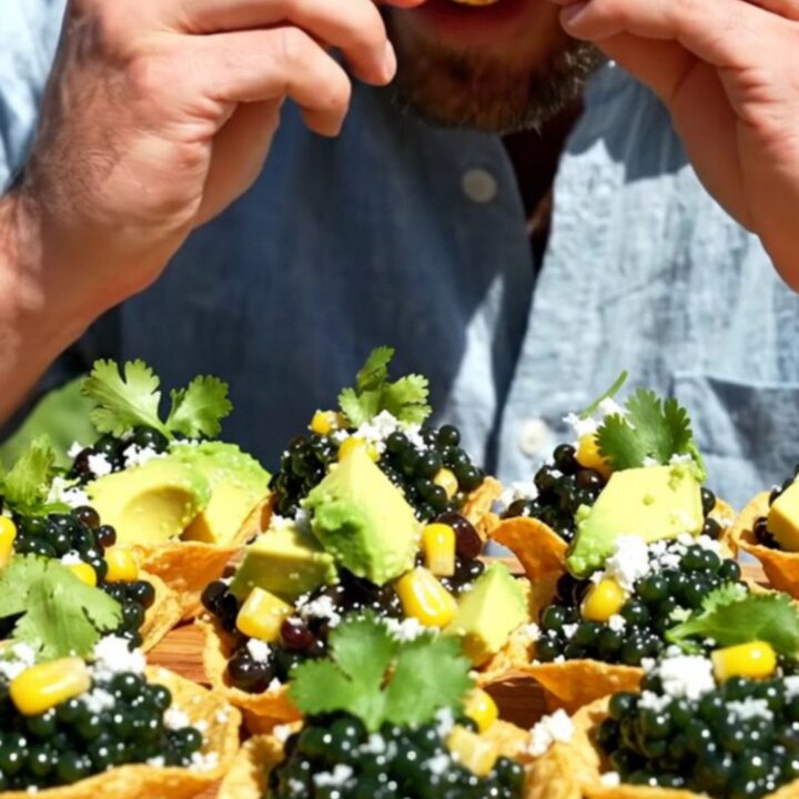 Mini tostada cups mounded with colorful cowboy caviar, diced avocado, and crumbled cotija cheese on a serving platter