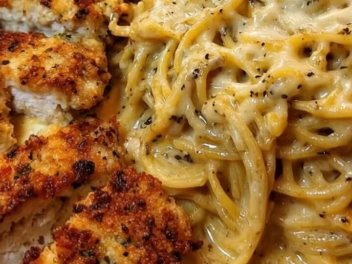 Crispy parmesan-crusted chicken slices over a mound of glossy cheesy spaghetti in a warm skillet