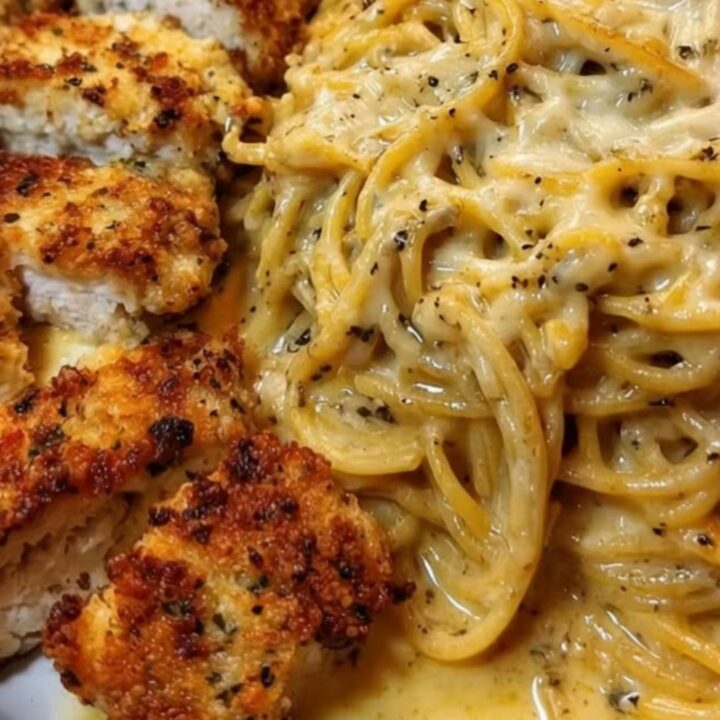 Crispy parmesan-crusted chicken slices over a mound of glossy cheesy spaghetti in a warm skillet