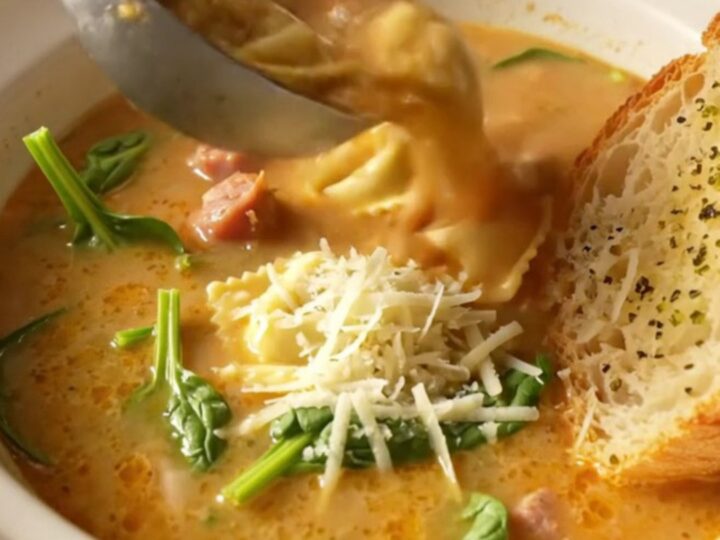 Slow-cooker creamy tortellini soup with Italian sausage crumbles and spinach in a deep bowl topped with grated parmesan