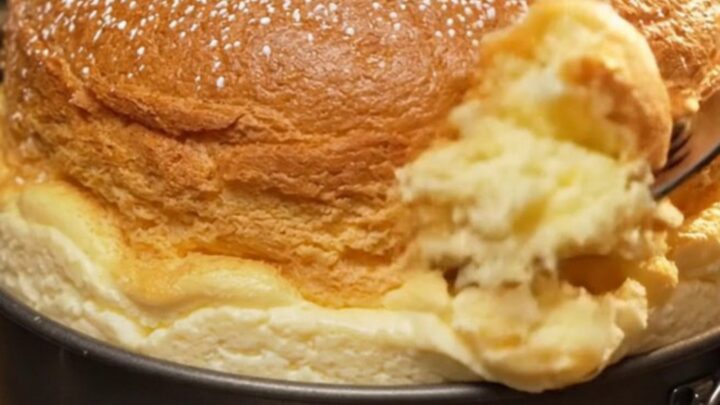 Golden Japanese soufflé cheesecake dusted with confectioners' sugar on a wooden board