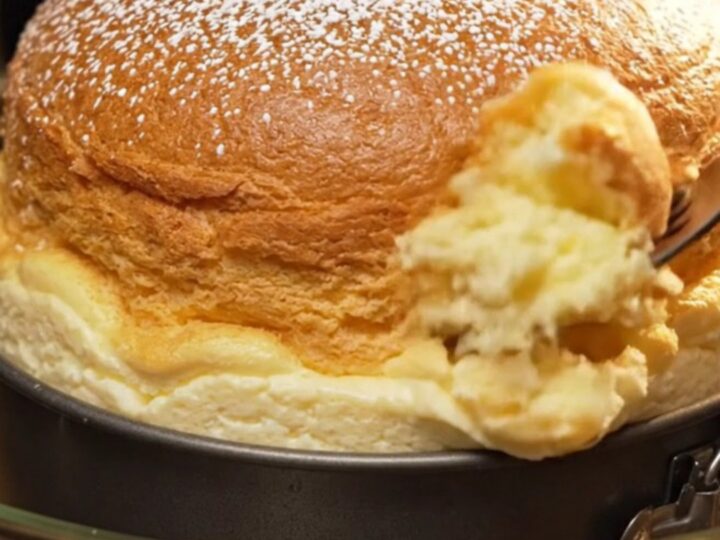 Golden Japanese soufflé cheesecake dusted with confectioners' sugar on a wooden board