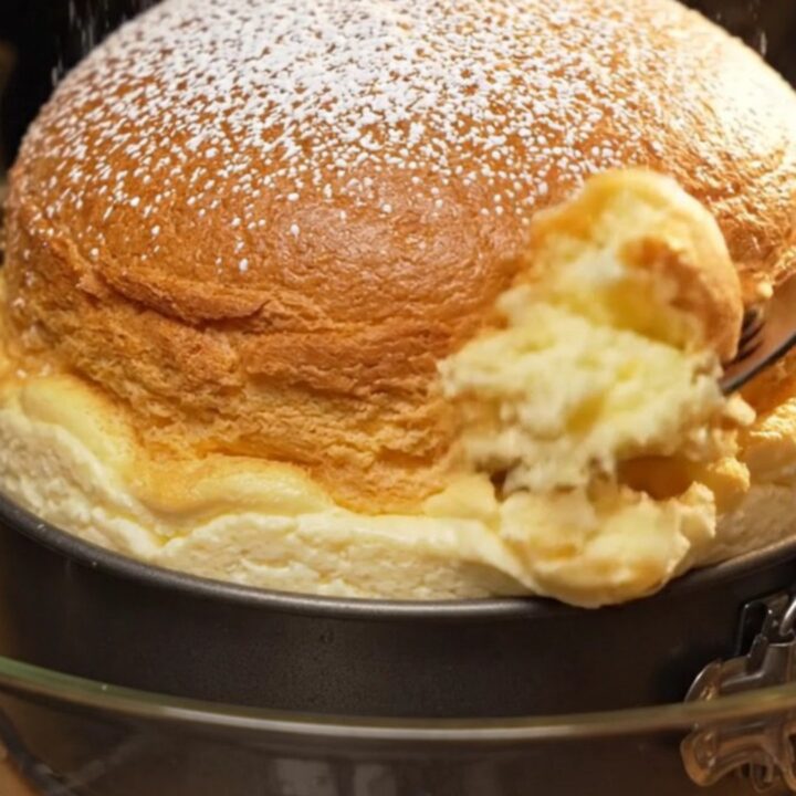 Golden Japanese soufflé cheesecake dusted with confectioners' sugar on a wooden board