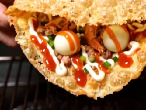Crispy Vietnamese rice paper pizza folded in half, blistered golden and zigzagged with chili sauce and mayonnaise on a board