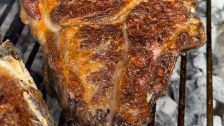 Sliced grilled bone-in ribeye with a dark charred crust and rosy juicy center on a white plate