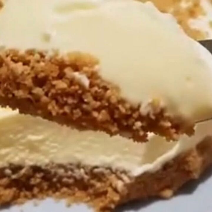A thick slice of condensed milk cheesecake with biscuit base and crumb topping lifted from a plate on a pie server