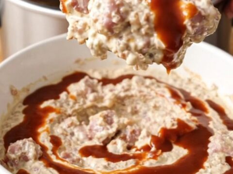 Thick crockpot BBQ sausage and bacon cream cheese dip swirled with barbecue sauce in a white bowl