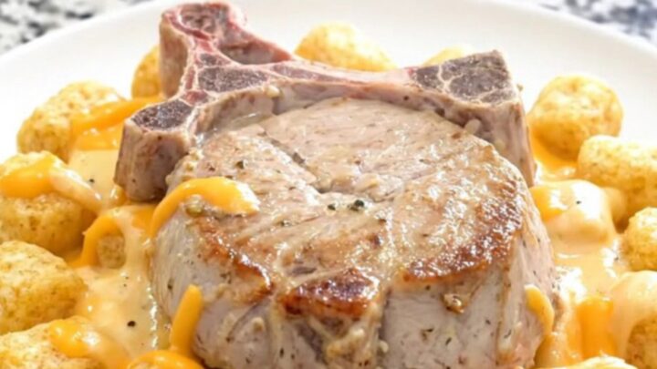 Slow cooker pork chop casserole with soft potato tots and thick creamy cheddar sauce in a black ceramic insert
