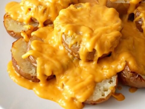 Crockpot cheddar scalloped potatoes served on a white plate, tender potato slices in thick cheesy cream sauce with light