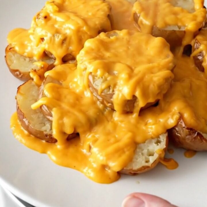 Crockpot cheddar scalloped potatoes served on a white plate, tender potato slices in thick cheesy cream sauce with light