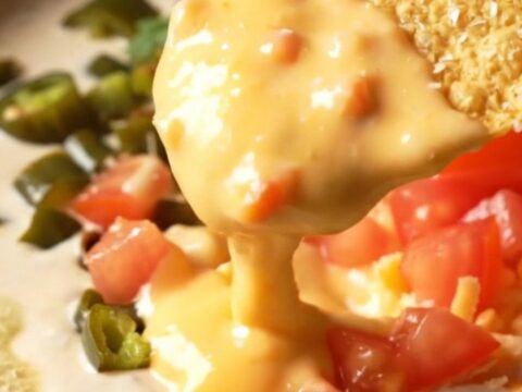 Glossy smoked gouda and Hatch green chile queso in a cast-iron skillet, a tortilla chip lifting a thick golden ribbon
