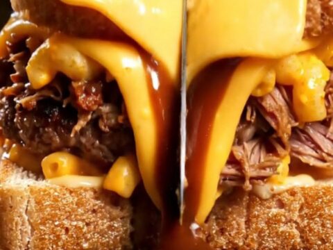 Texas toast patty melt cut in half showing layers of smash patty, pulled pork, mac and cheese, and melted colby jack