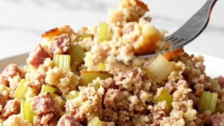 Slow cooker sausage and sage stuffing scooped onto a white plate with golden edges and browned sausage crumbles