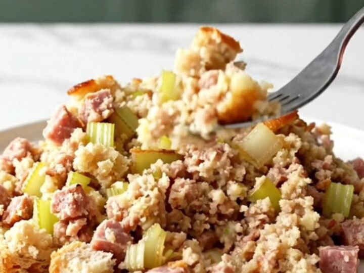 Slow cooker sausage and sage stuffing scooped onto a white plate with golden edges and browned sausage crumbles