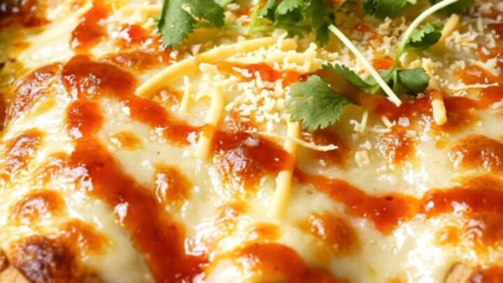 Spoon lifting a short rib birria enchilada from a bubbling clay dish, trailing poblano cream sauce and melted Oaxaca cheese