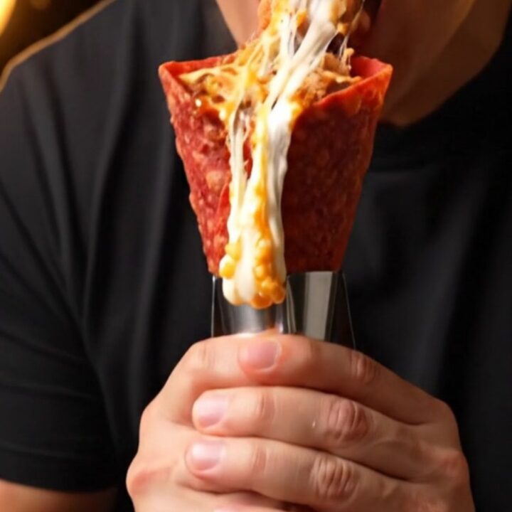 Crispy birria cone overflowing with melted Oaxaca cheese and braised beef, lime squeezed over the top