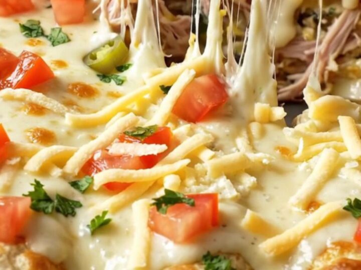 Spinach artichoke queso chicken enchilada lifted from a baking dish with strings of melted mozzarella and creamy white
